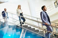 Three people walking down the stairs at a office.