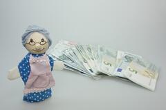 Lalka przedstawiająca babcię obok jej oszczędności emerytalnych