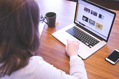 Młoda kobieta dorabiająca pracą zdalną przy komputerze