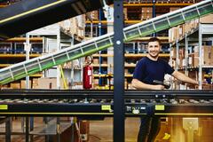 Smiling man standing behind a conveyor belt 
