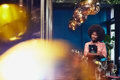 Smiling woman walking through restaurant holding menu cards.