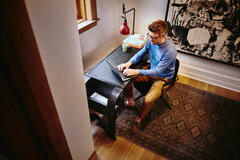 Bird view of male sitting at a desk working on his laptop