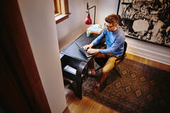 Bird view of male sitting at a desk working on his laptop