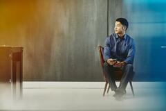 Man with cell phone sitting on a chair. China. Primary color: blue.