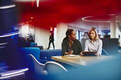 Business women having a meeting. Primary colors: red, blue and turquoise.