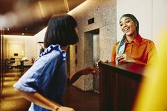 Smiling hotel receptionist helping a guest.