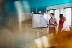 Team working on a Google Jamboard in an office. Primary colors: yellow and turquoise. 