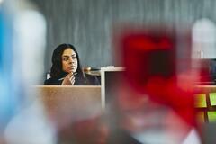 Woman watching over her desk. India. Primary color: red.