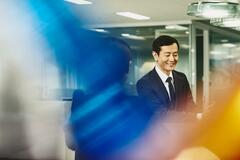 Man and woman talking in an office. Japan. Primary color: blue.