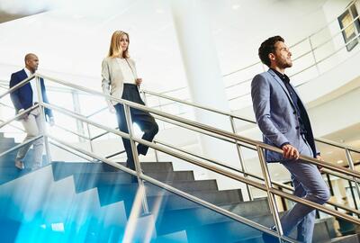 Three people walking down the stairs at a office.