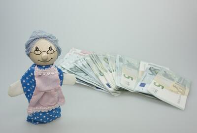 Lalka przedstawiająca babcię obok jej oszczędności emerytalnych