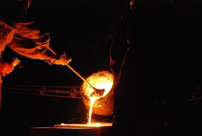Pracownik odlewni mieszający tyglem płynny metal