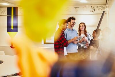 Group of colleagues talking in an office, smiling.