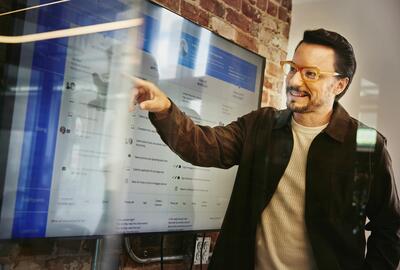 Male standing in front of a screen and pointing at data