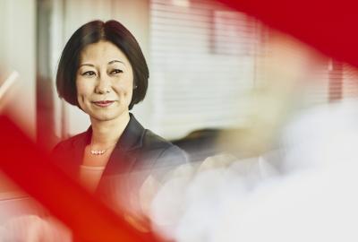 Woman in suit smiling. Japan. Primary color: red.