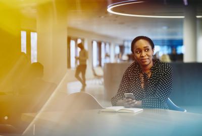 Business woman in an office smiling. Primary color: yellow.