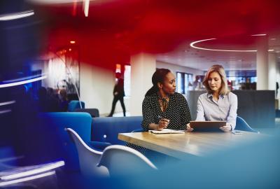 Business women having a meeting. Primary colors: red, blue and turquoise.