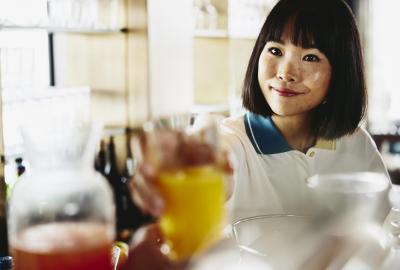 Smiling woman bartender handing a glass of orange juice.