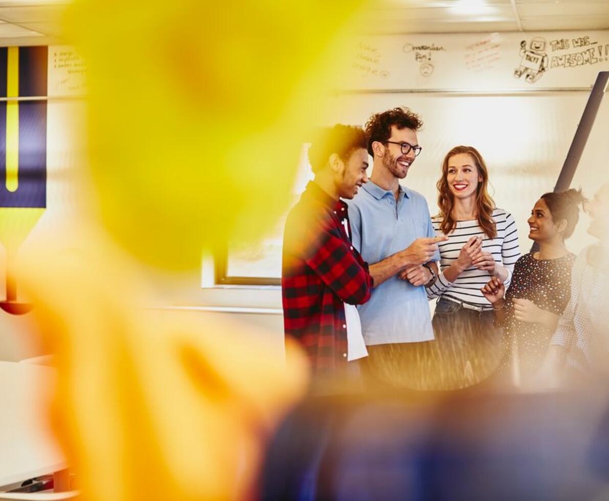 Group of colleagues talking in an office, smiling.