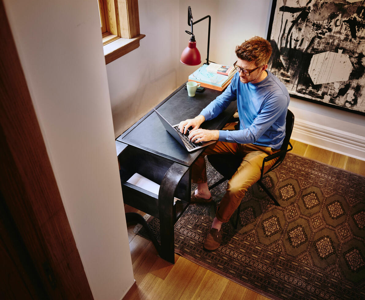 Bird view of male sitting at a desk working on his laptop
