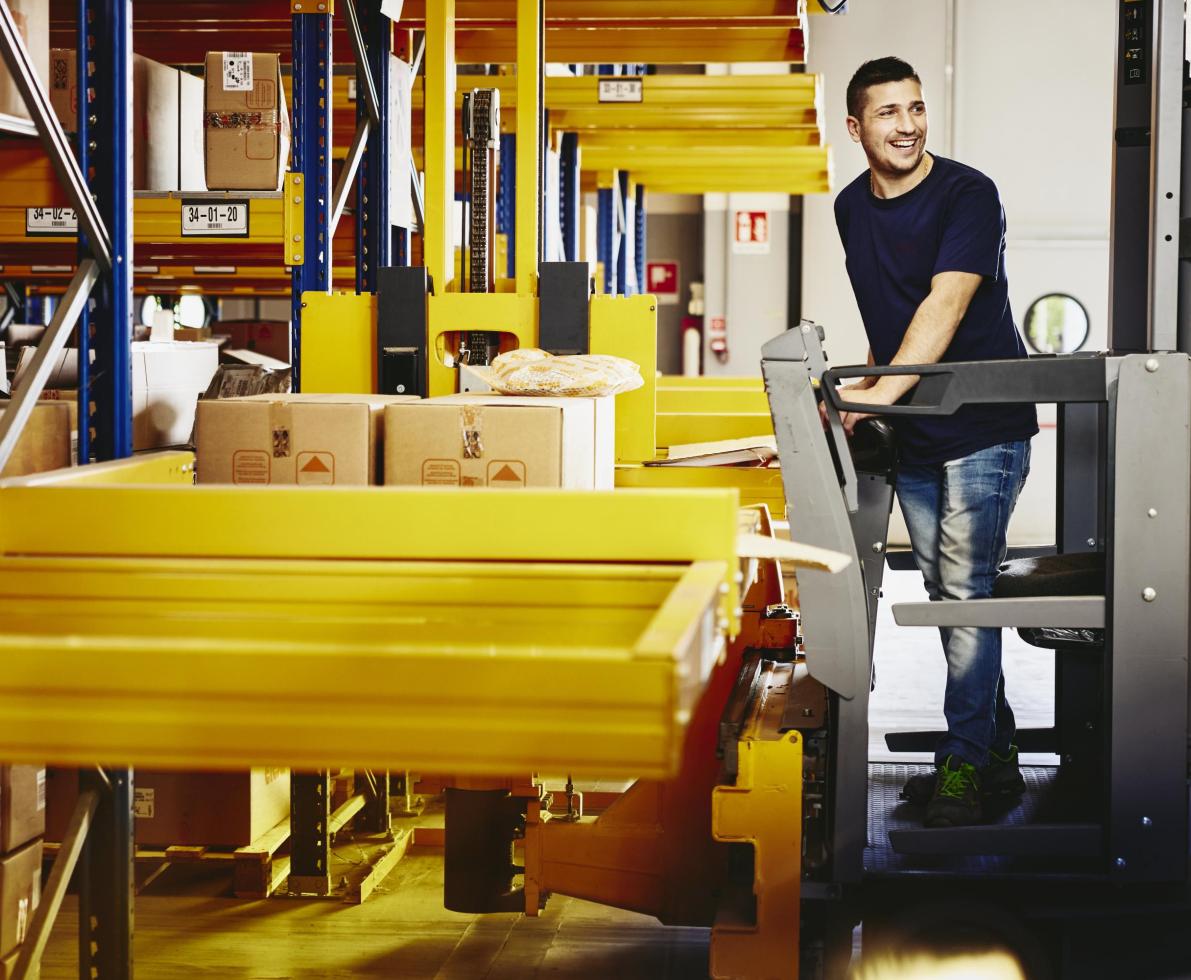 Smiling man standing on a forklift.