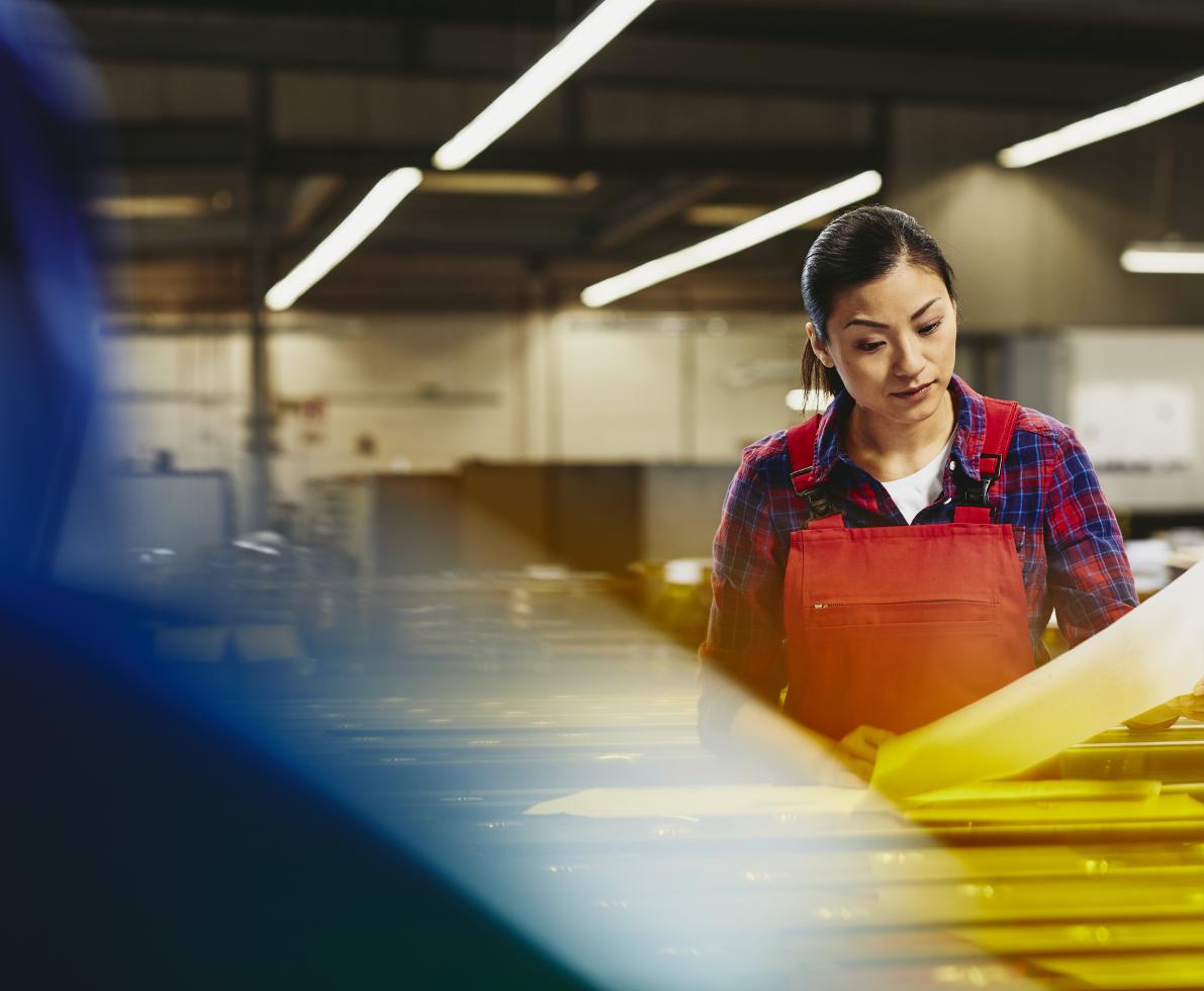 Female operator reading from paper. Factory. Tech environment. Asian woman. Primary color red. Secondary colors blue and yellow.