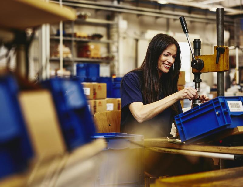Smiling woman working on a production site. Smiling woman working on a production site.