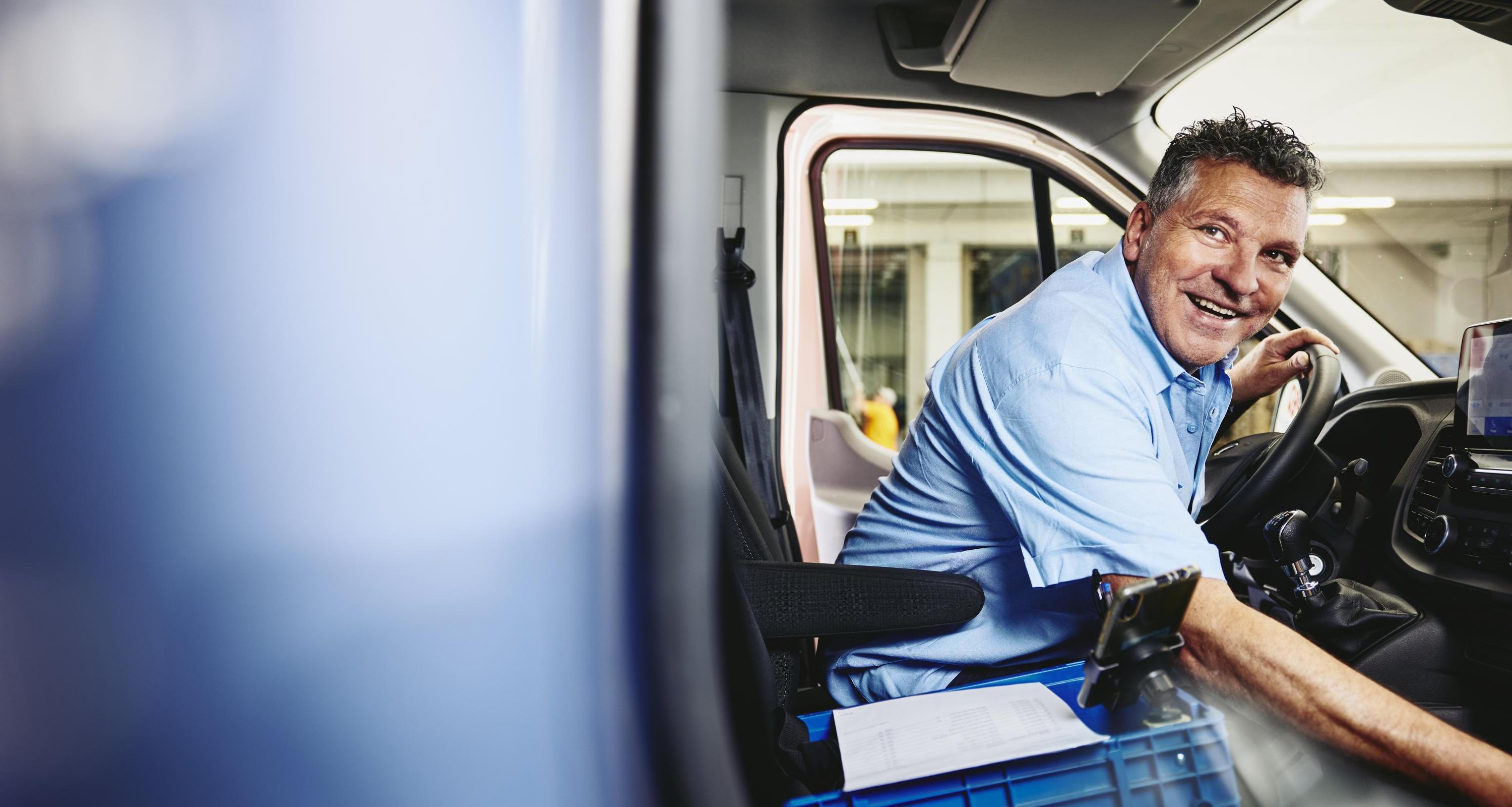 Smiling man sitting in driver's seat of a logistics truck